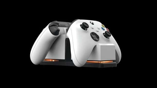 Two white Xbox controllers are in a charging dock. 