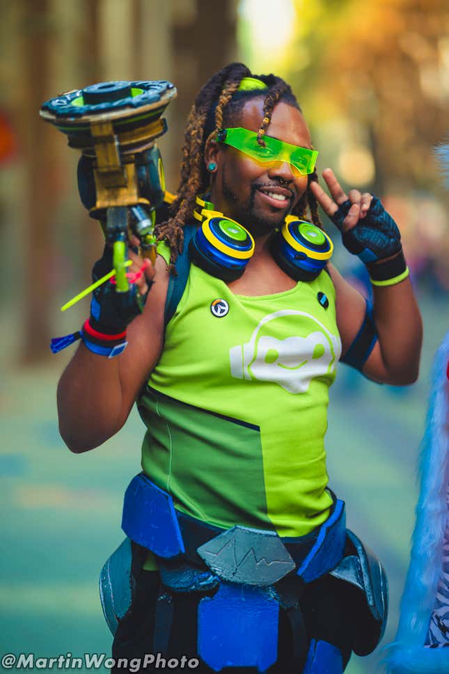 A Lucio cosplayer holds their weapon and smiles. 
