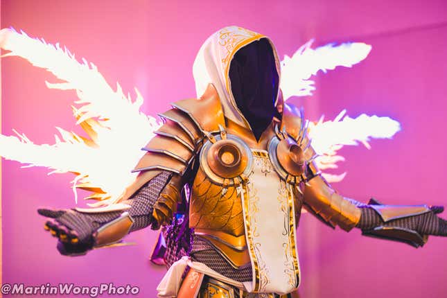 A cosplayer holds their arms out while dressed as Diablo III character, Tyrael. 