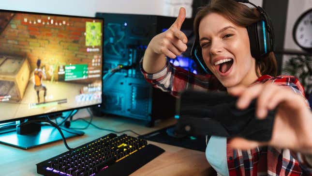 An image shows a woman taking a selfie while playing a game. 